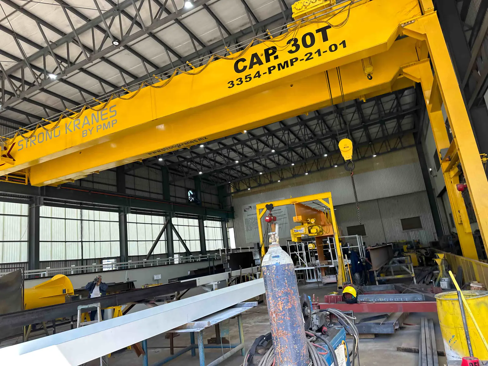 Grúa semigantry amarilla Strong Kranes de 30 toneladas dentro de un taller industrial