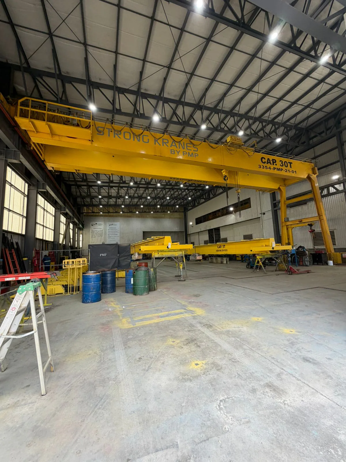 Grúa semigantry amarilla Strong Kranes vista desde el piso de una nave industrial