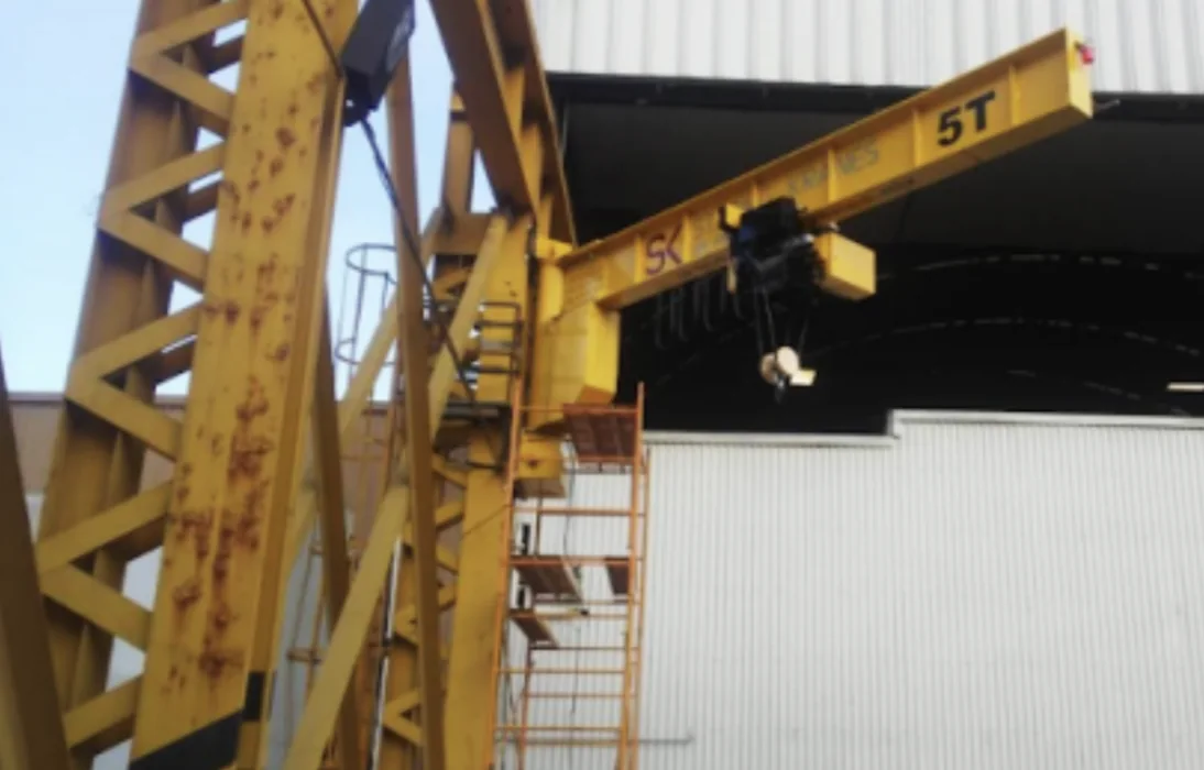 Wall-mounted jib crane attached to a column inside an industrial facility