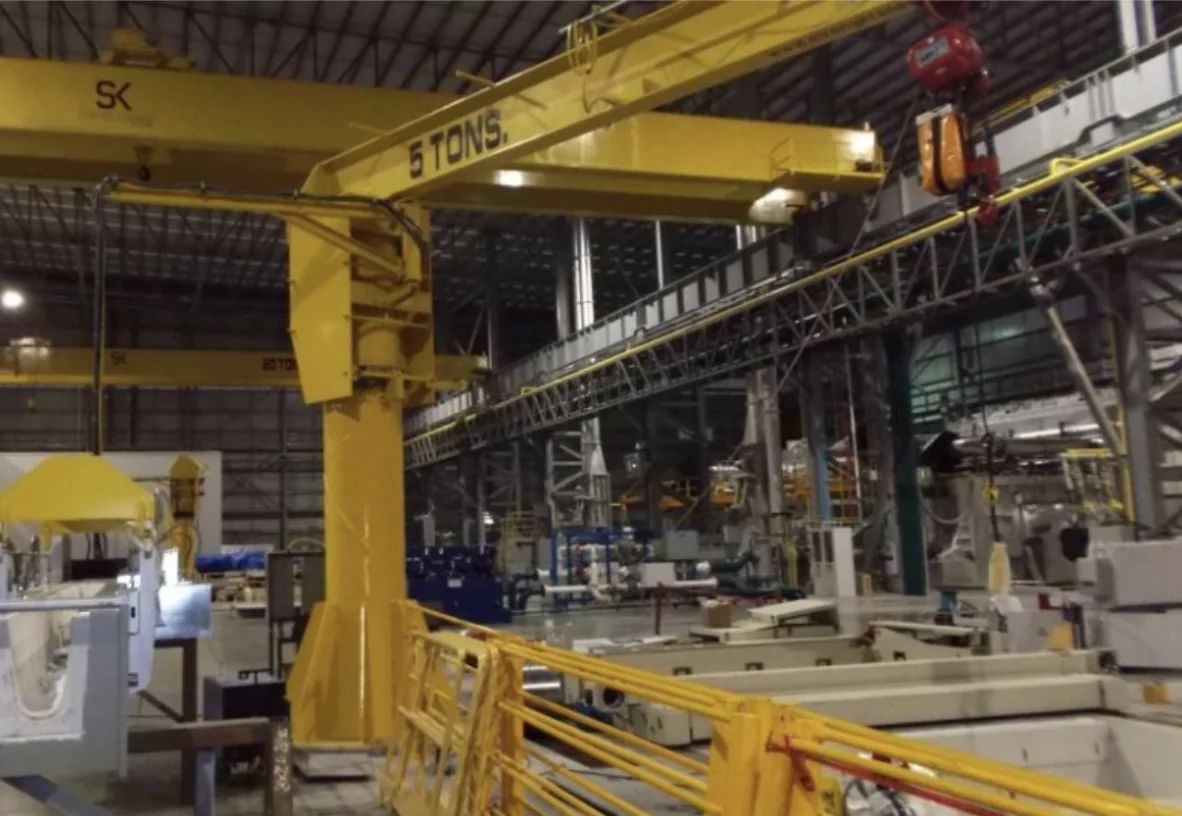 Yellow Strong Kranes jib crane operating above a production line