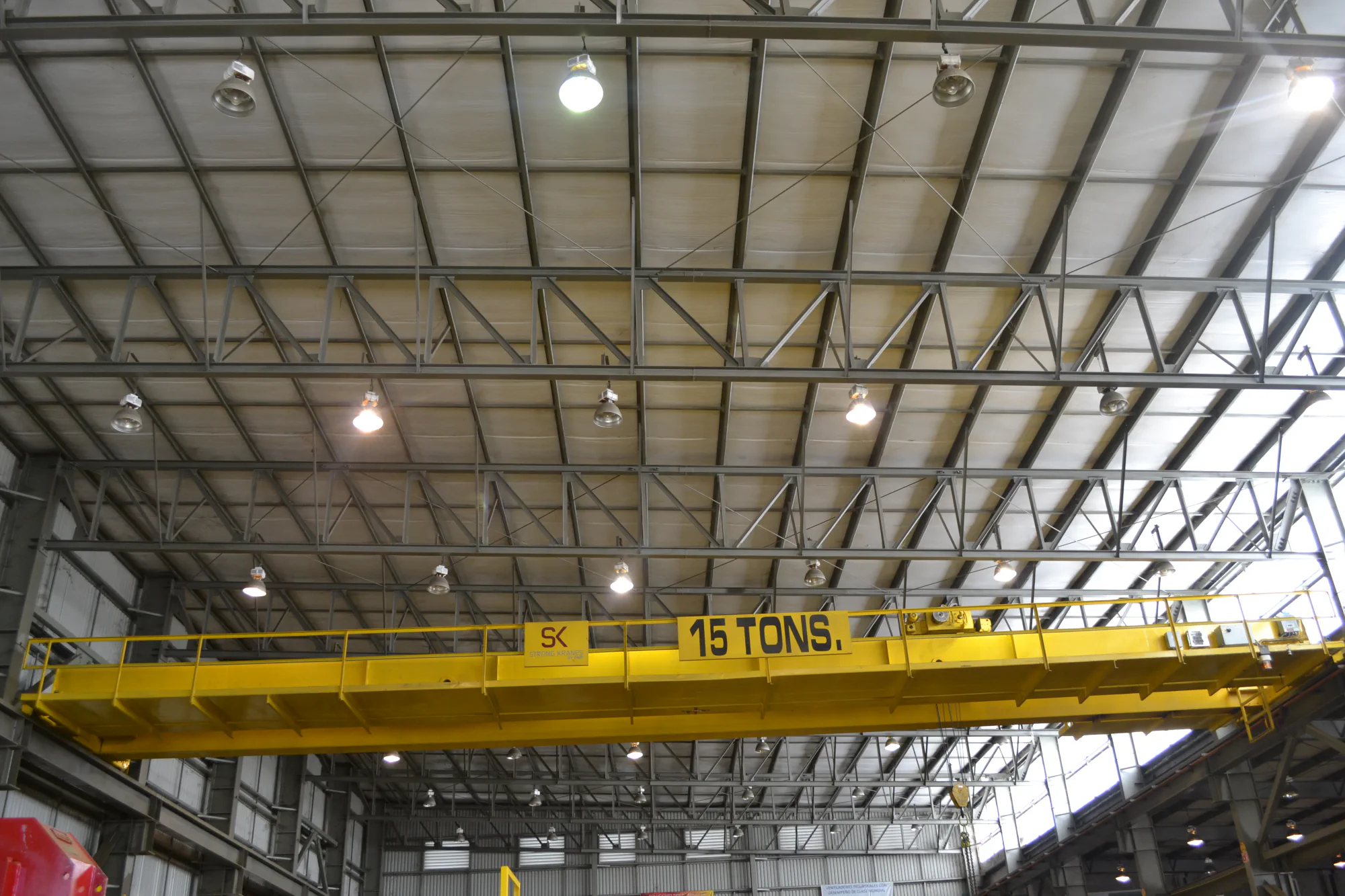 Grúa viajera bipuente amarilla Strong Kranes de 15 toneladas dentro de una nave industrial