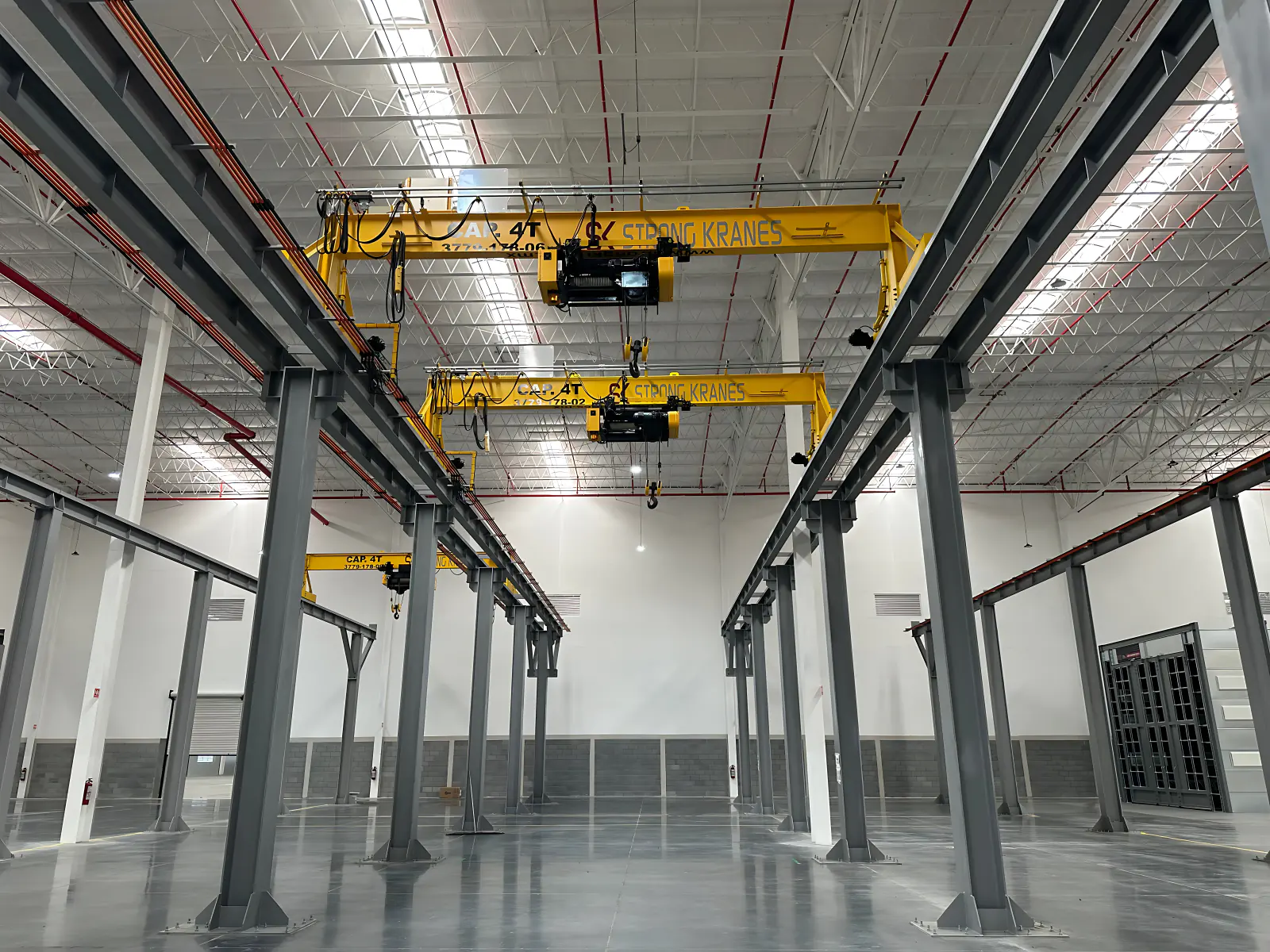 Tres grúas viajeras monopuente amarillas Strong Kranes instaladas en una nave industrial