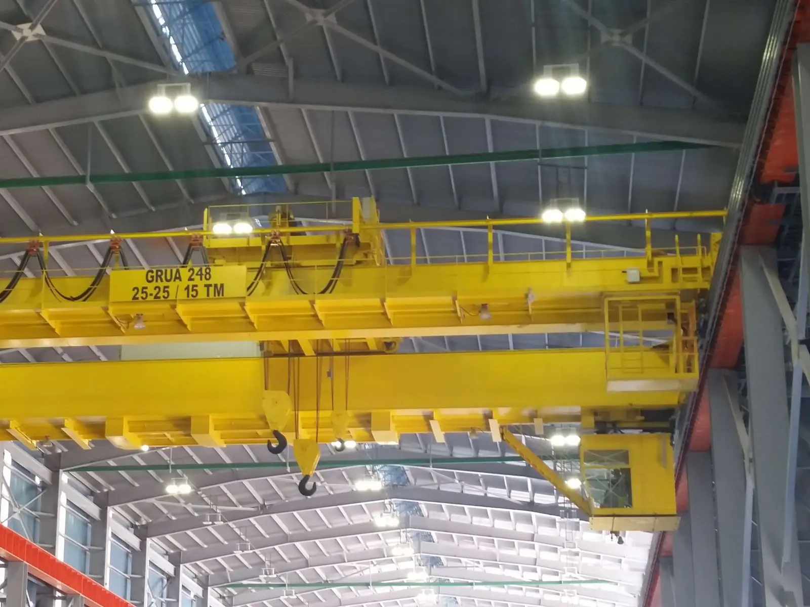 Grúa especial bipuente amarilla de servicio pesado con cabina de operación en una nave industrial