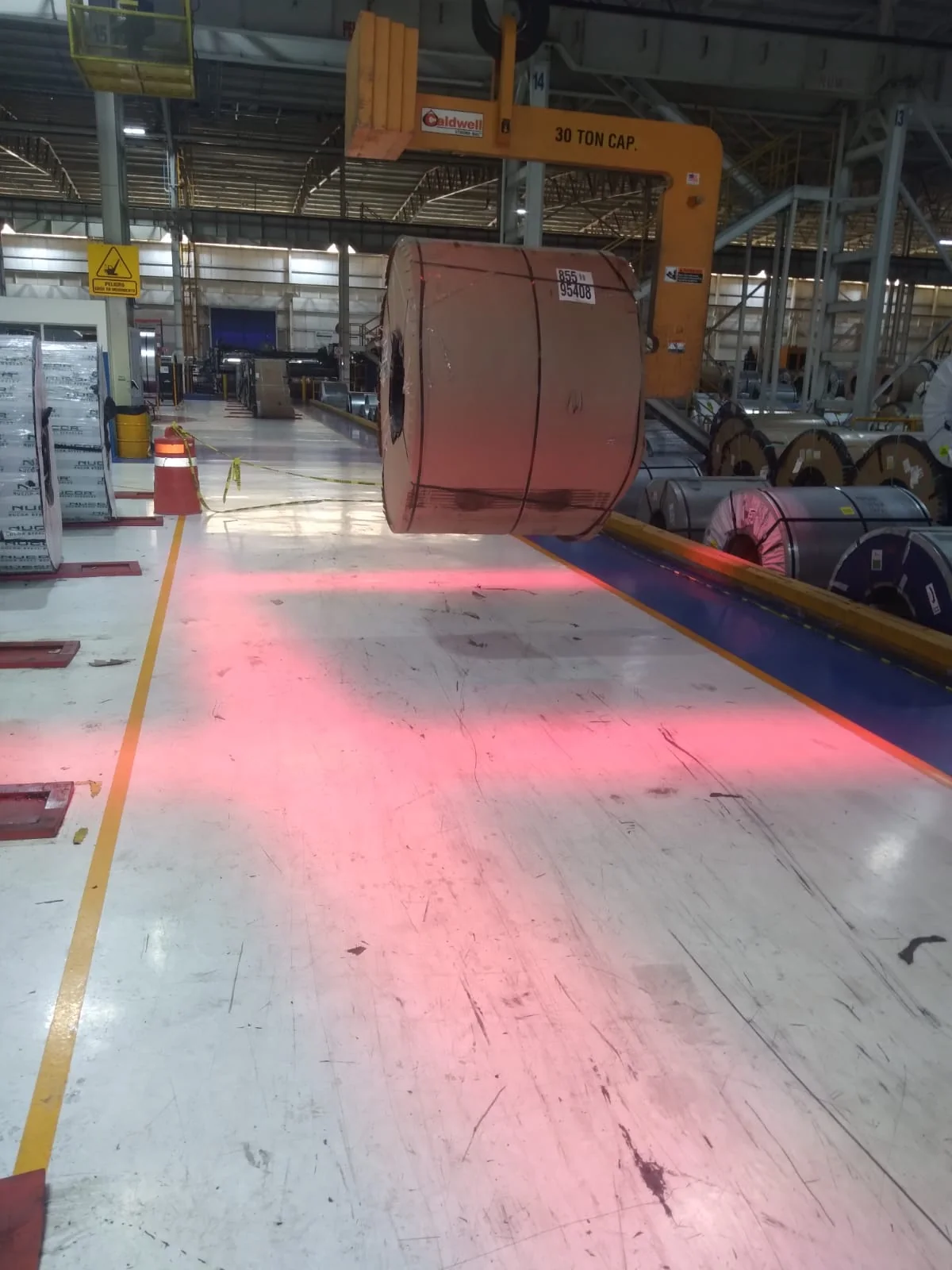 Proyección lineal roja que delimita el área de tránsito junto a bobinas de acero