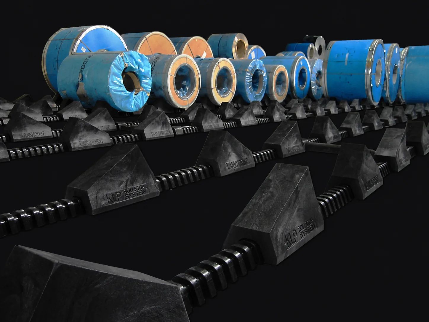 Sistema modular Lankhorst RollStop para almacenamiento seguro de bobinas de acero sobre fondo oscuro